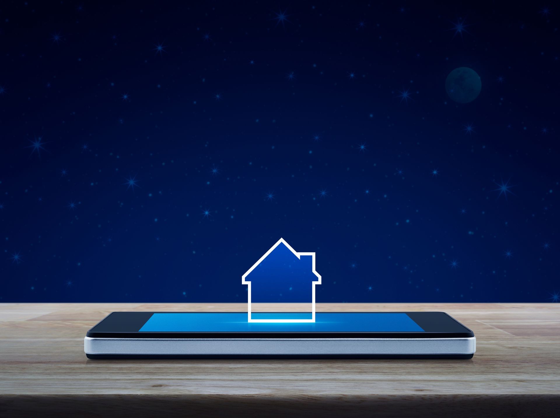 House icon with copy space on modern smart mobile phone screen on wooden table over fantasy night sky and moon, Businesss real estate online concept House icon with copy space on modern smart mobile phone screen on wooden table over fantasy night sky and moon, Businesss real estate online concept